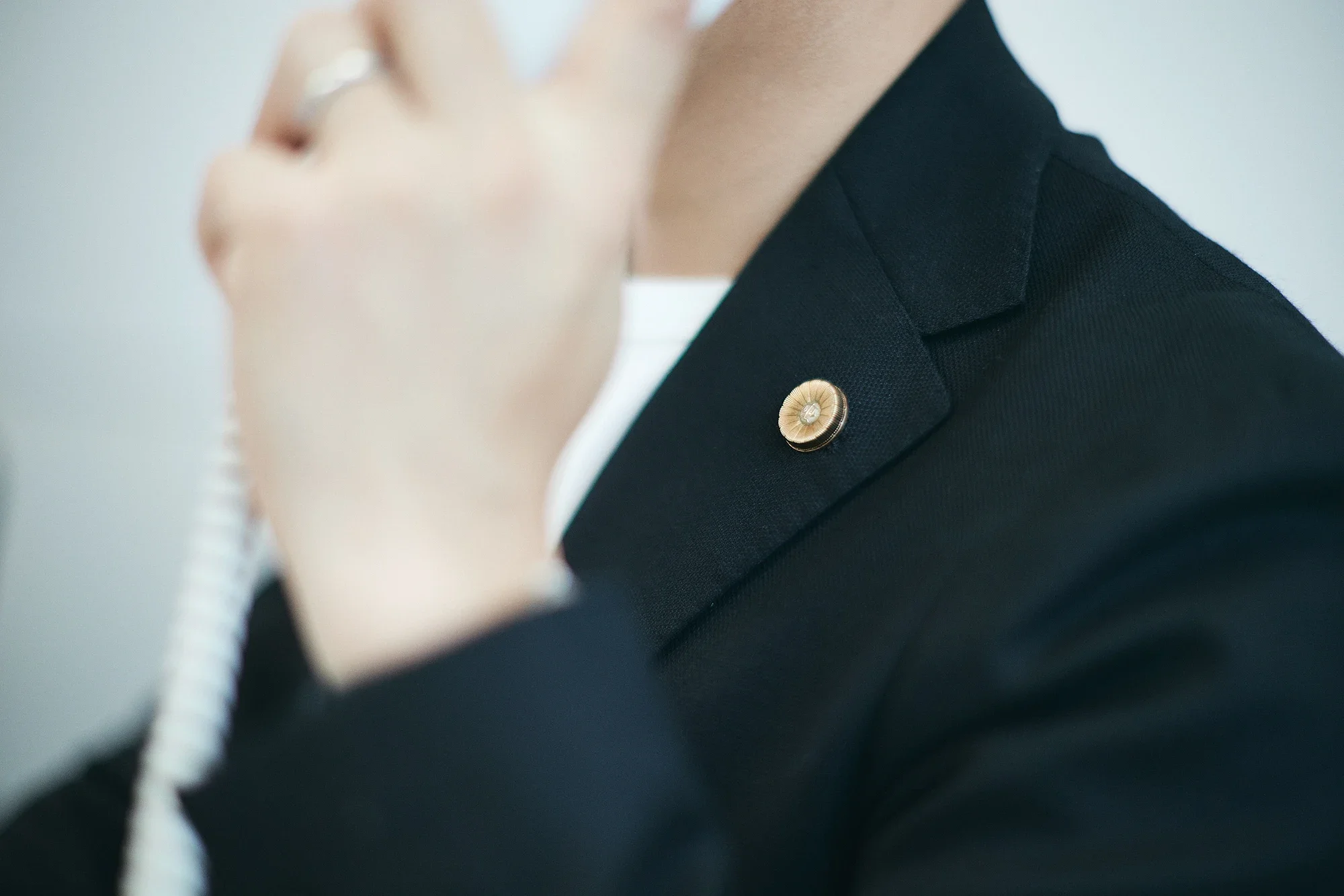 電話で相談を受けている弁護士の胸元と弁護士バッジ（記章）のクローズアップ。プロフェッショナルな責任感と信頼の象徴であるバッジを強調したイメージ写真。