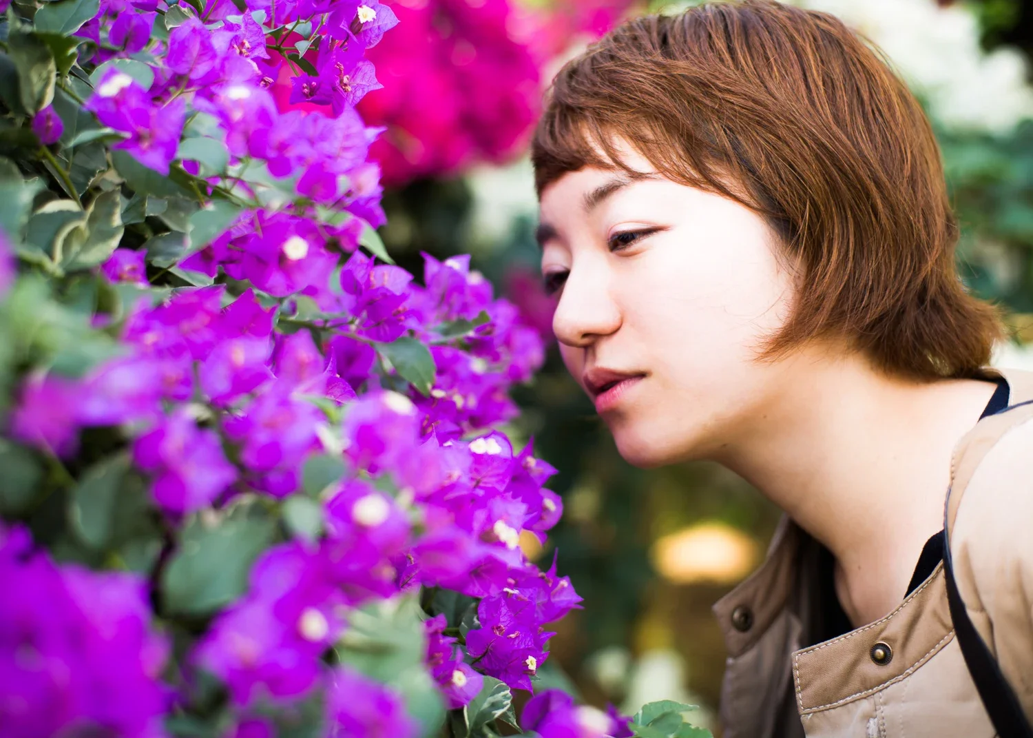 紫色の花のそばに微笑む女性の横顔