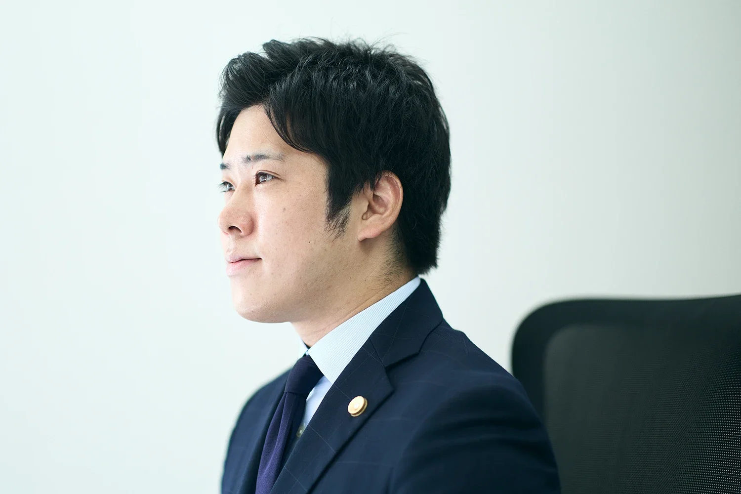 会社の制服を着た男性が横向きに座っている。