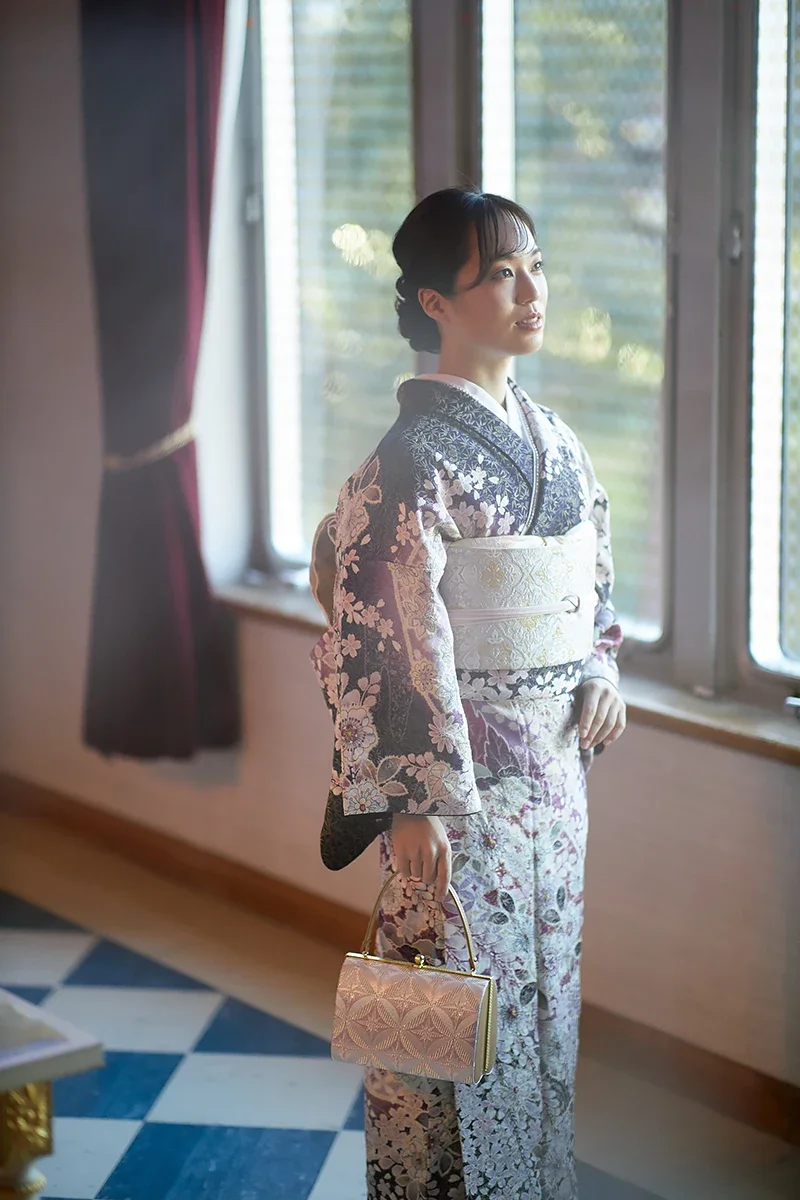 着物を着た女性が窓辺で立っている写真