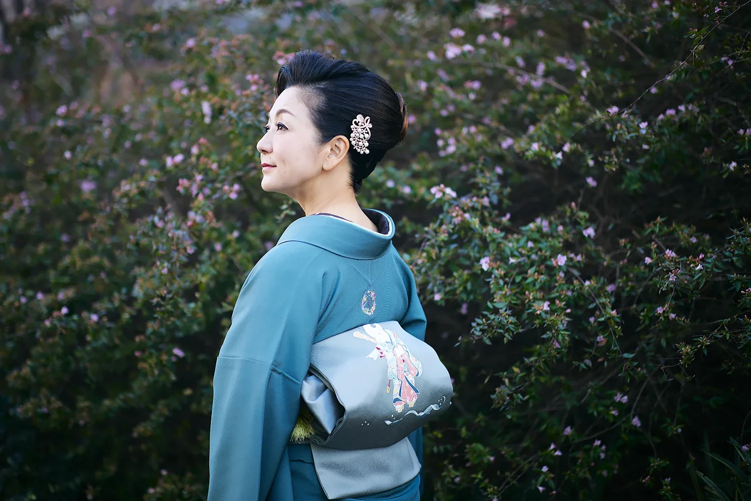 紫色の花が咲く木の前で振り返る着物姿の女性