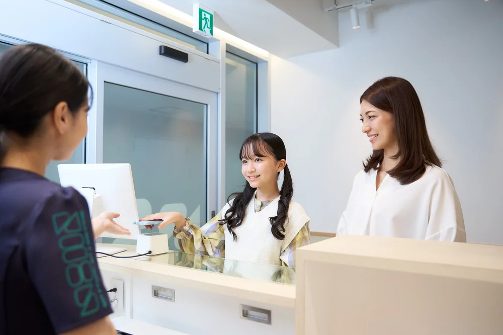 矯正歯科の受付で患者さんを迎える様子の撮影事例（大宮SHIN矯正歯科）