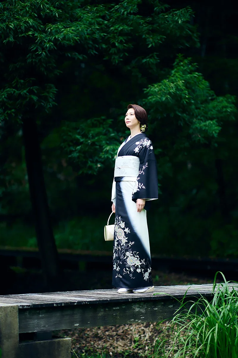 緑豊かな公園で和服を着た女性が立っている