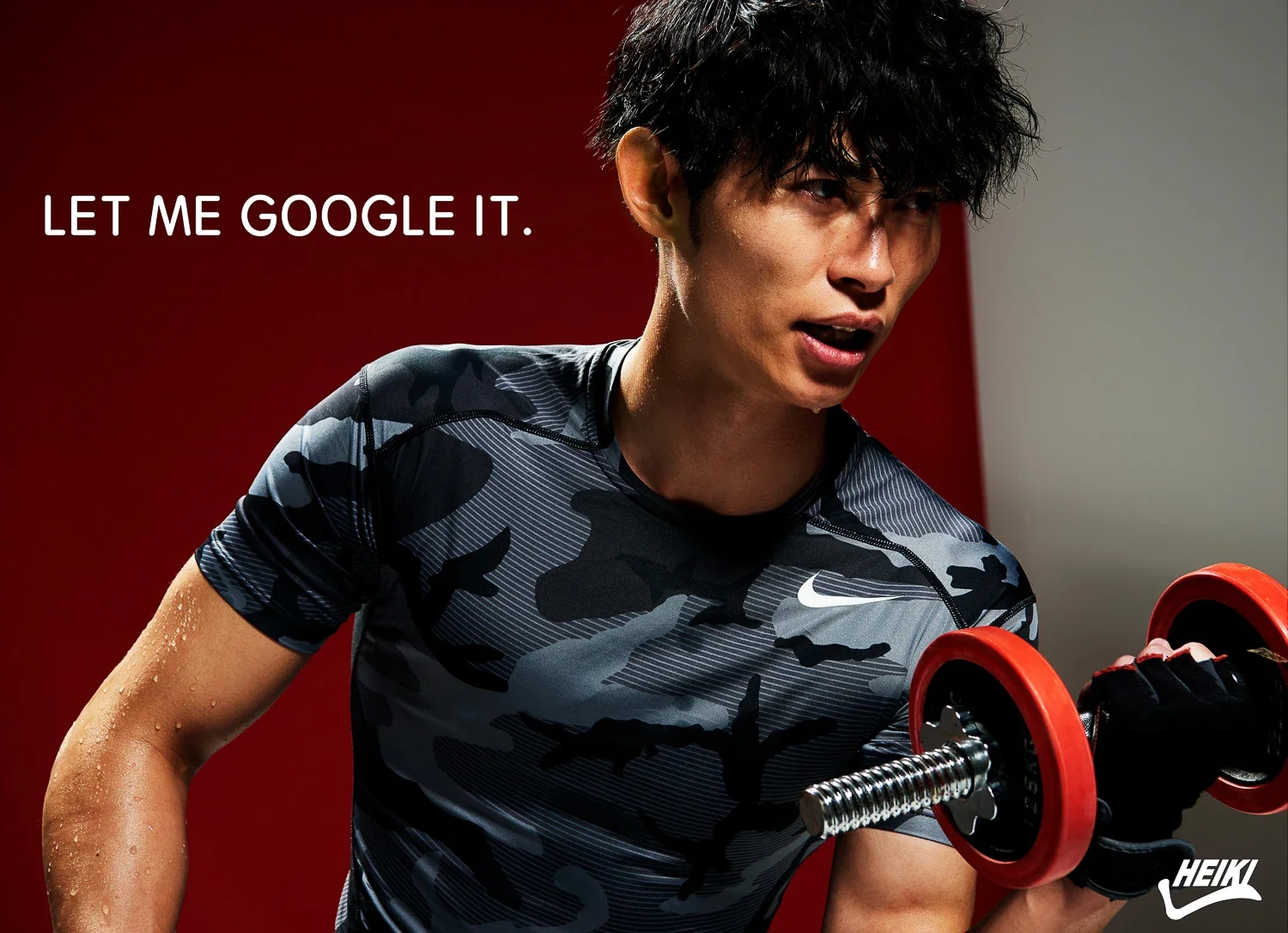 スポーツウェアを着た男性がダンベルを持ち上げている。背景は赤と灰色。左上に白字で「LET ME GOOGLE IT.」と書かれている。