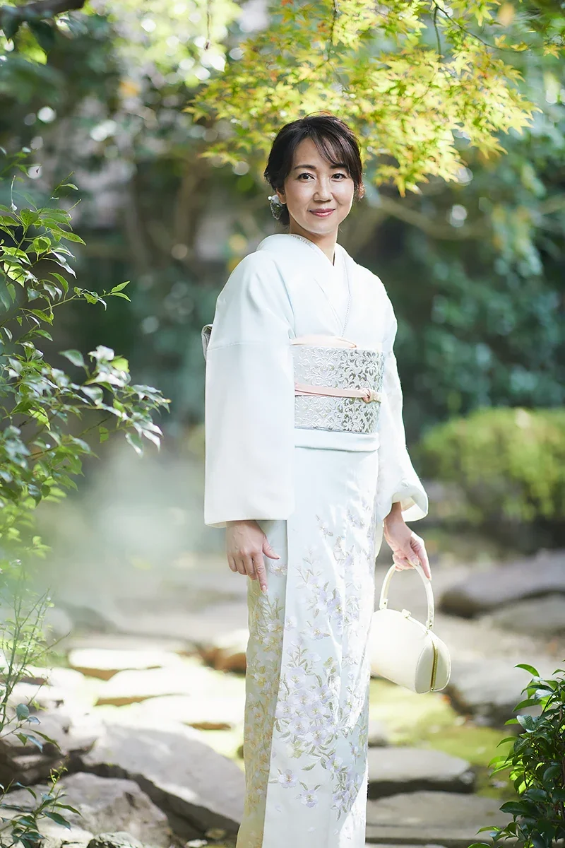 庭園で着物を着た女性が池の周りを歩いている