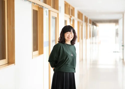 笑顔の女性が学校の廊下に立っている