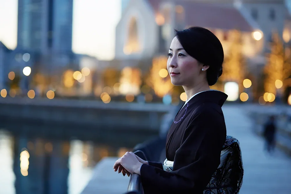 夜の都市の橋の上に立つ着物を着た女性の横顔