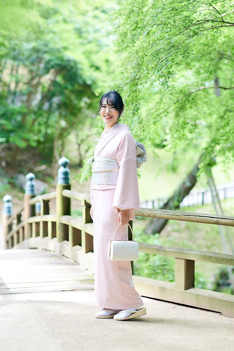 緑豊かな公園で、着物を着た女性が微笑んでいる写真