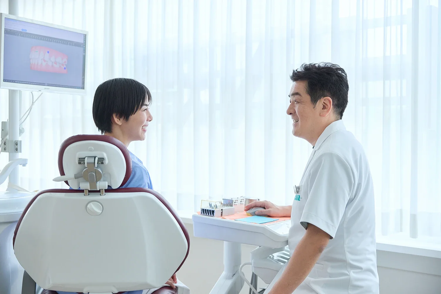 歯科医院で患者と歯科医師が笑顔で会話しているシーン