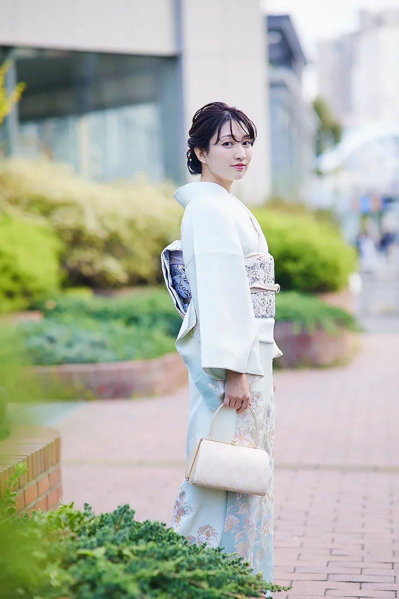 着物を着た女性が外の歩道に立っている写真