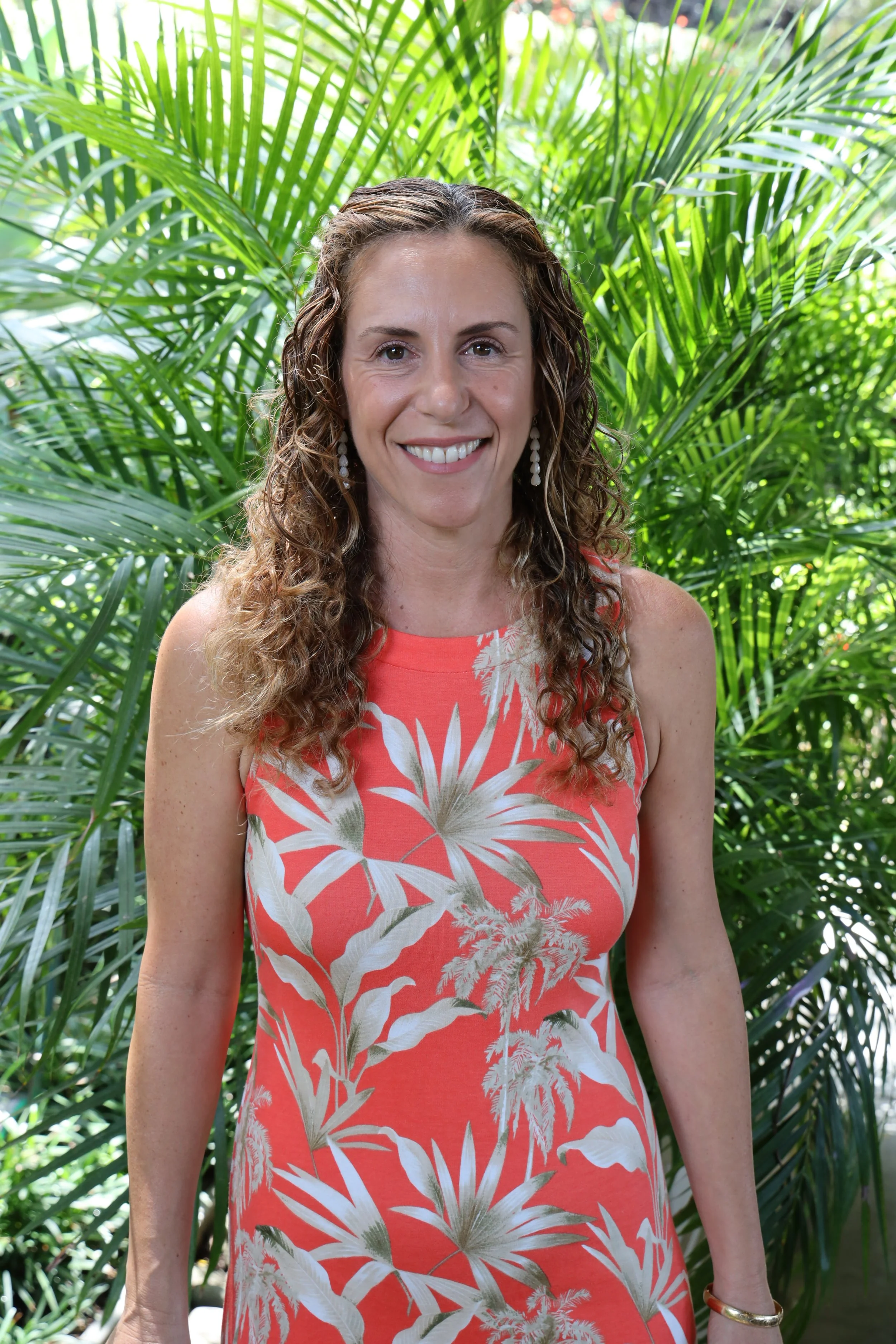 Portrait of abstract painter Calie Durant smiling outdoors in front of lush tropical greenery.
