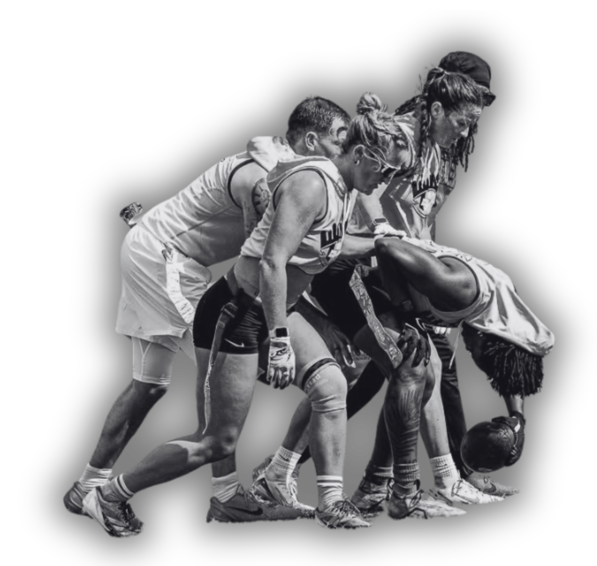 Black and white photo of a group of football players in a huddle, with one player bending down holding a football, on a black background.