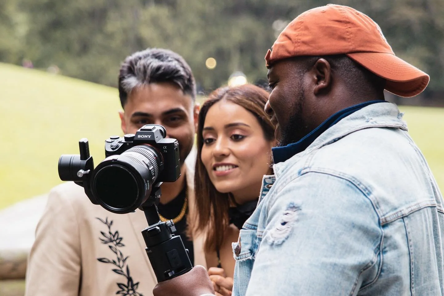 Three friends looking at a camera outdoors grass background