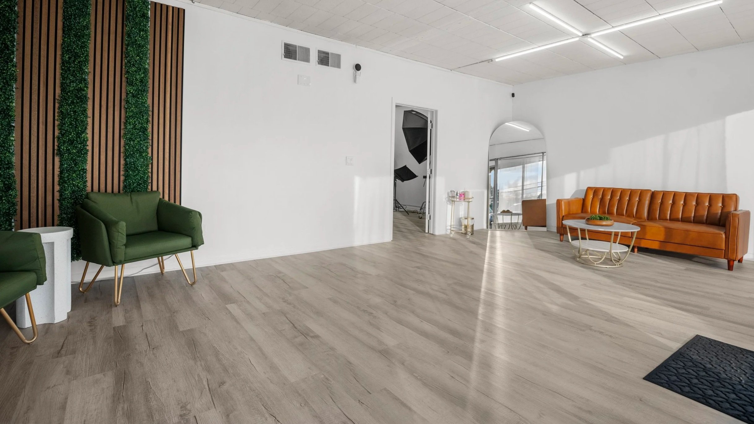 Rumble Creative Studios entryway room in Milford, CT with a podcast corner, mirror, couch, and doorway leading into the full studio space.