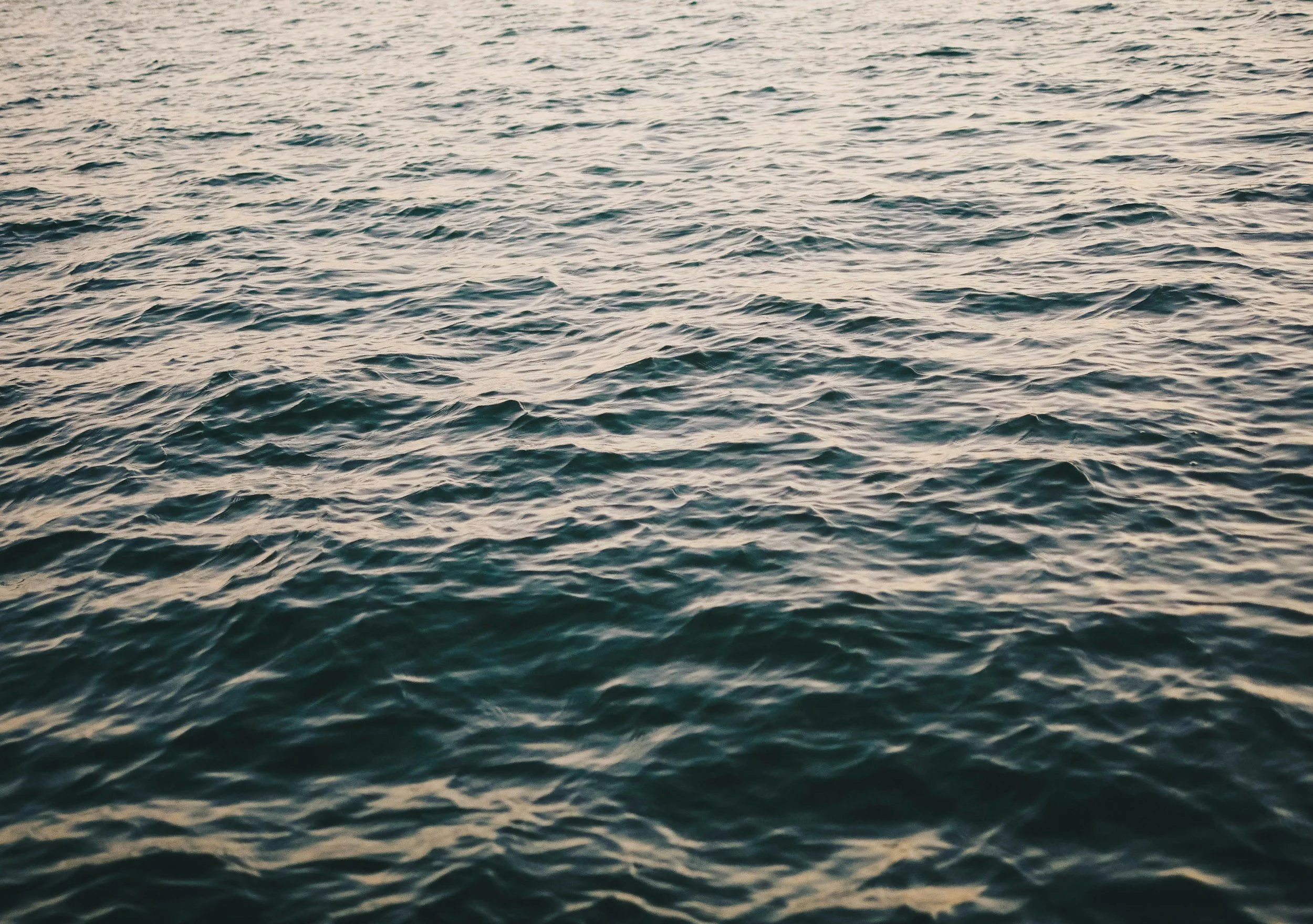 Open ocean water with small waves at sunset or sunrise.