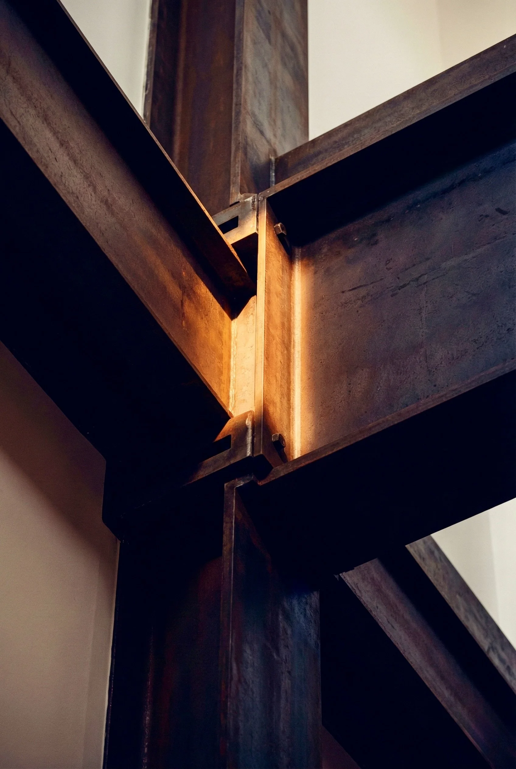 Close-up of a metal staircase structure with wooden steps, showing the joints and lighting reflecting off the metal.
