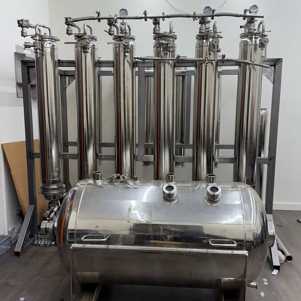 Stainless steel industrial distillation or chemical processing equipment with multiple vertical columns and a large horizontal tank.