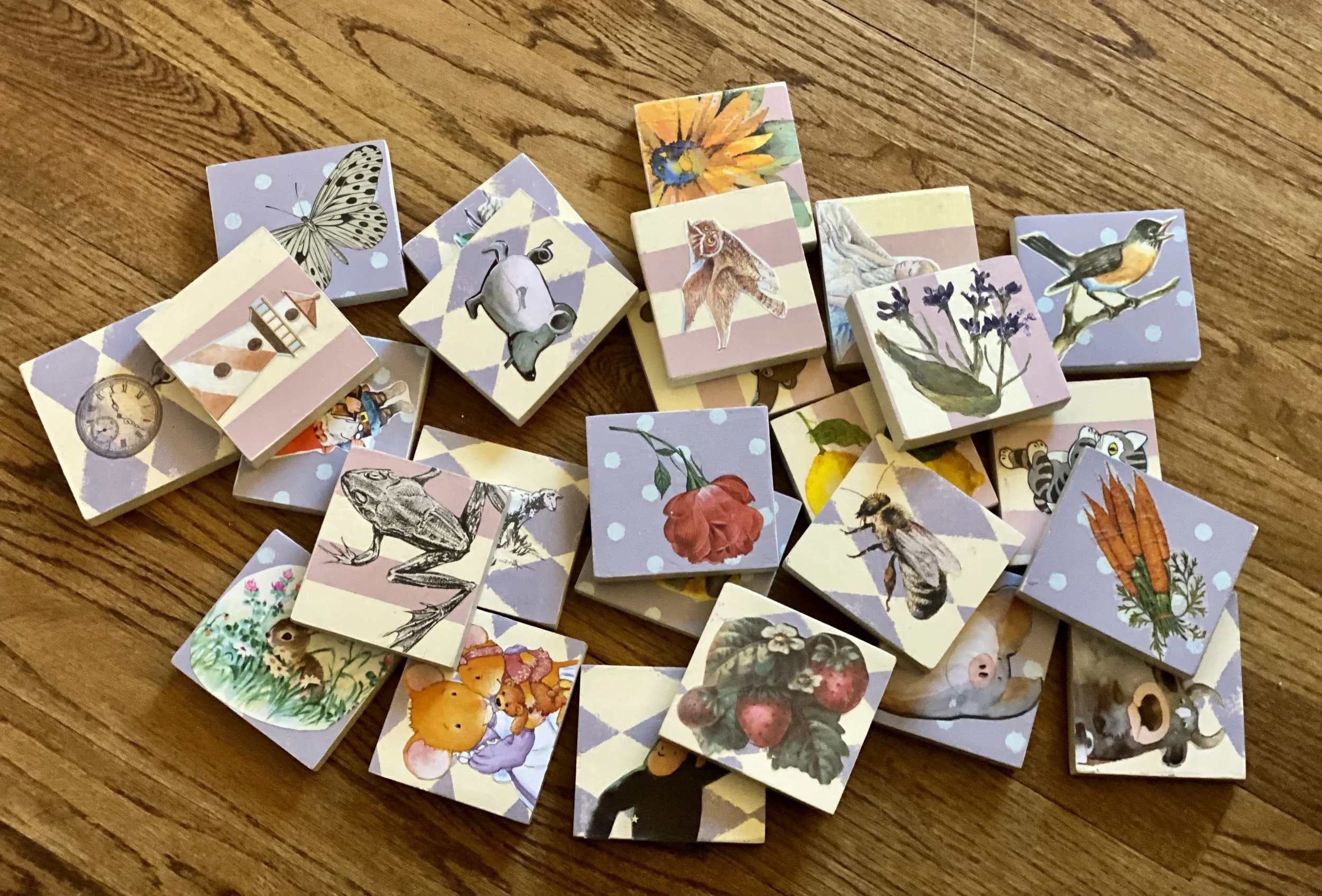 A collection of illustrated picture cubes featuring animals, plants, and objects scattered on a wooden surface.