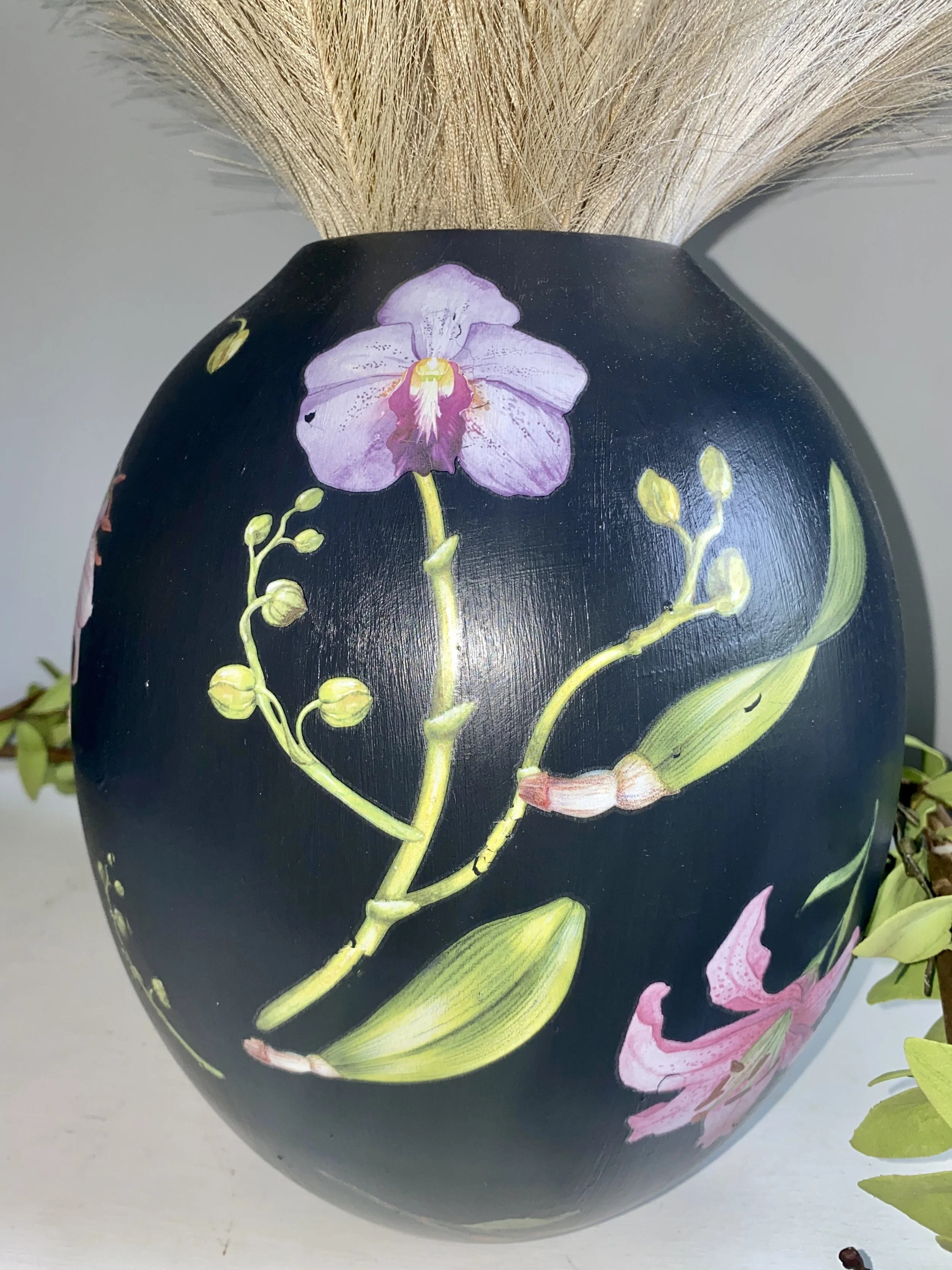 Black vase with hand-painted pink and purple orchids and green leaves
