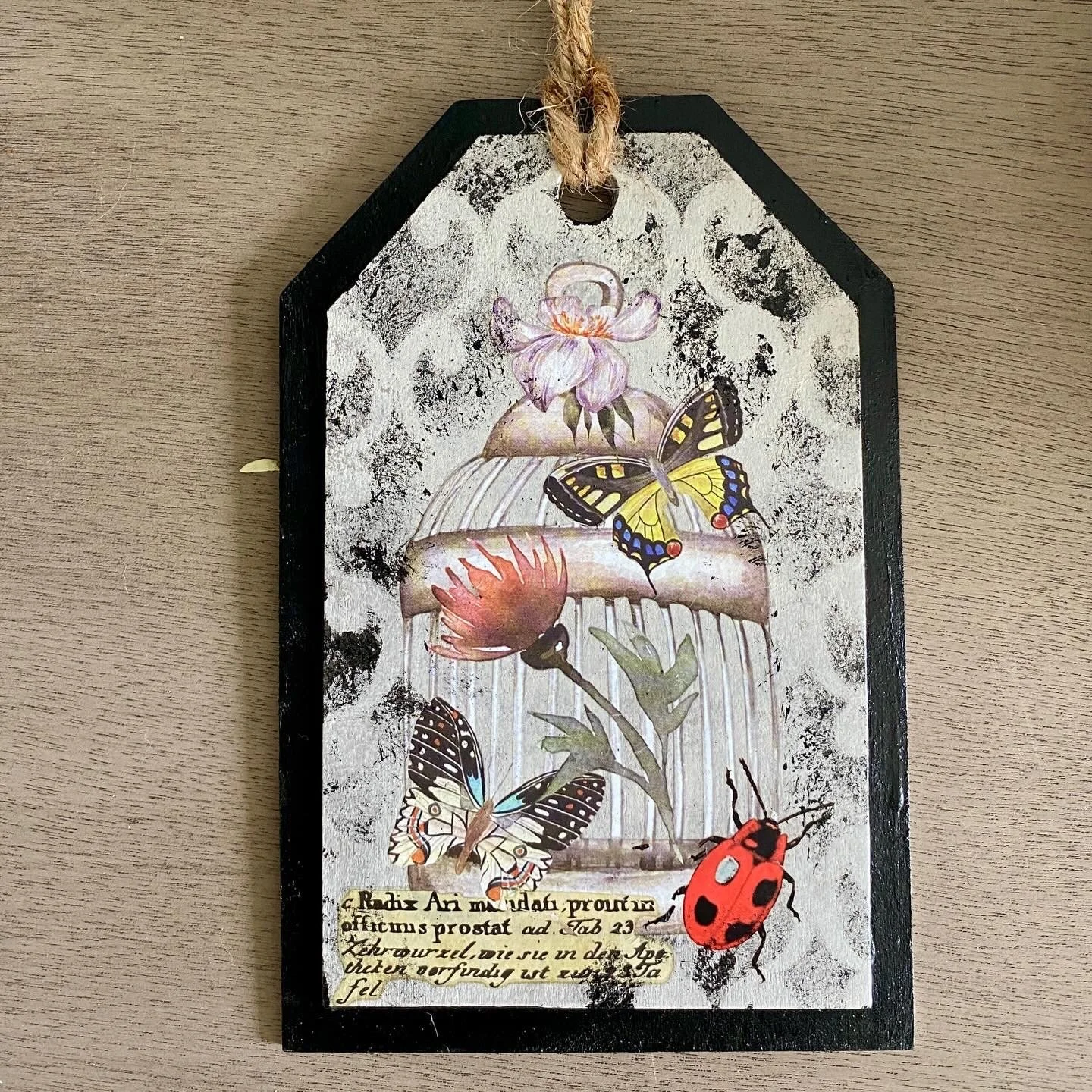 Decorative plaque with painted butterflies, flowers, and handwritten text on a wooden surface.