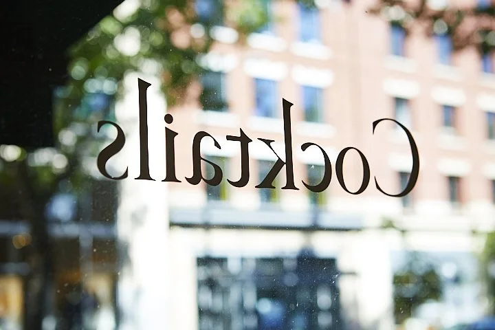 Reflection of a city street in a glass window with the word 'locketill' written on it.