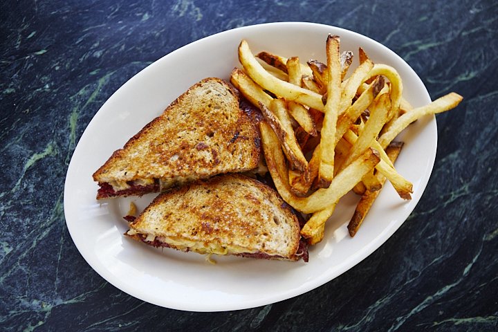 Grilled cheese sandwich and French fries on a white oval plate