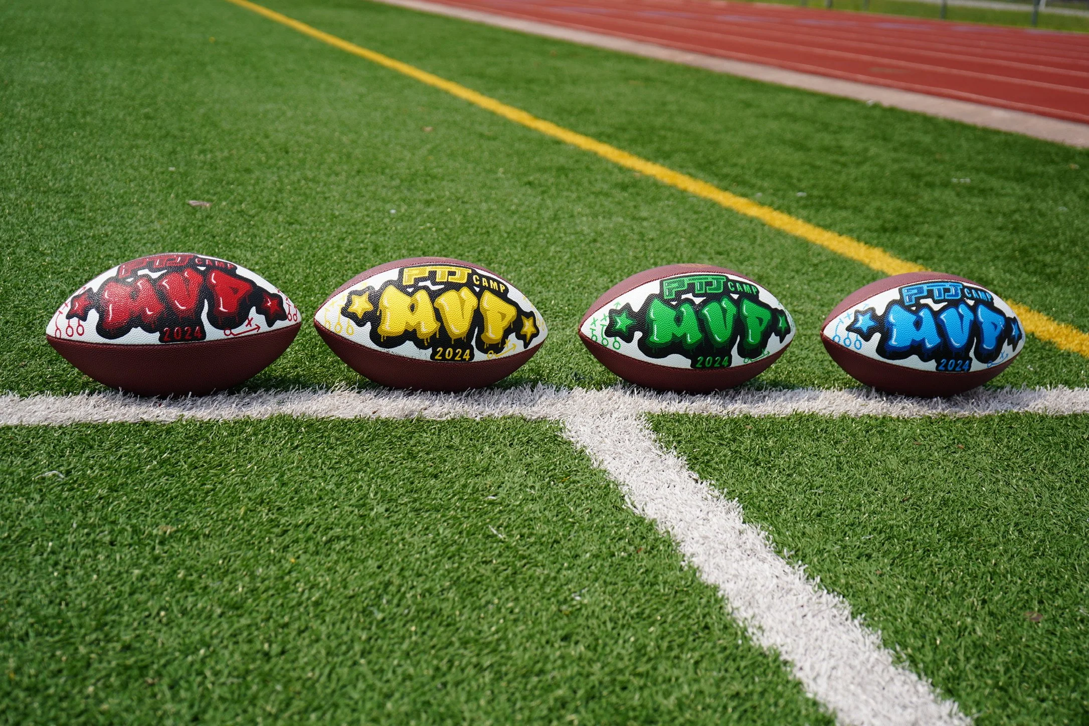 Four footballs with graffiti-style text spelling 'MVP' in red, yellow, green, and blue, arranged on a green football field with yellow and white lines.