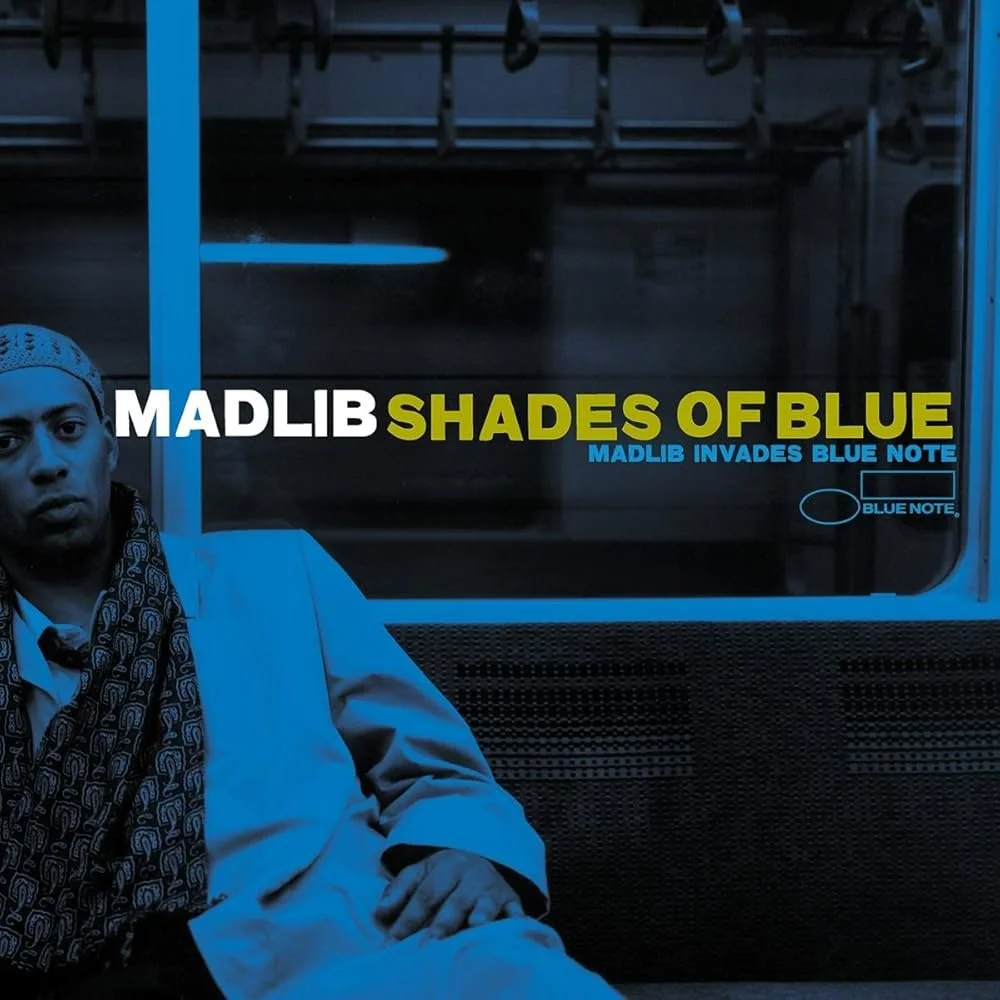 Album cover of Madlib's 'Shades of Blue,' featuring a black and white photo of Madlib sitting, with the title and artist name in bold letters.
