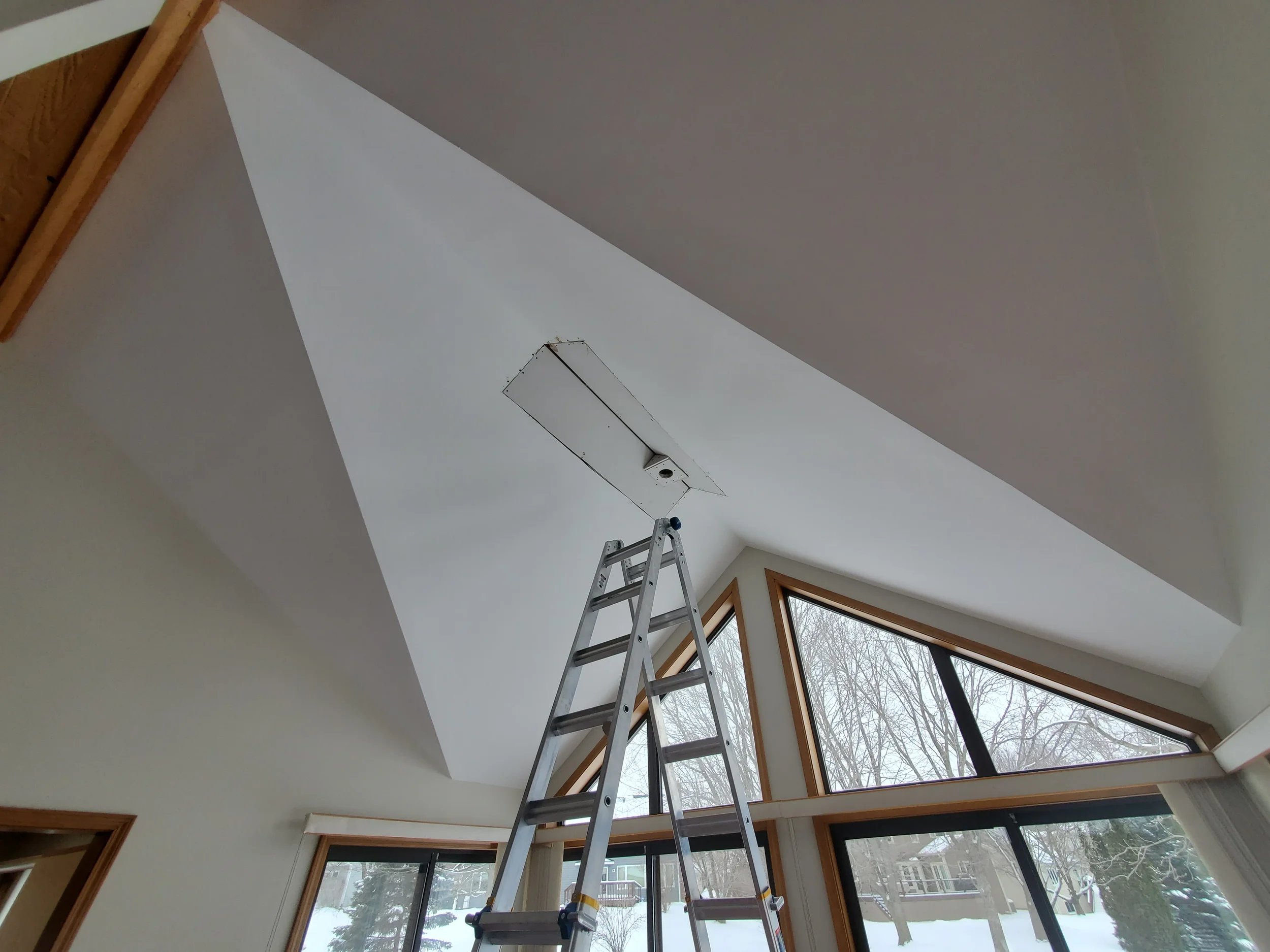 New drywall installation and structural repair after water damage in a high-ceiling living room by Kora Pro Painting.