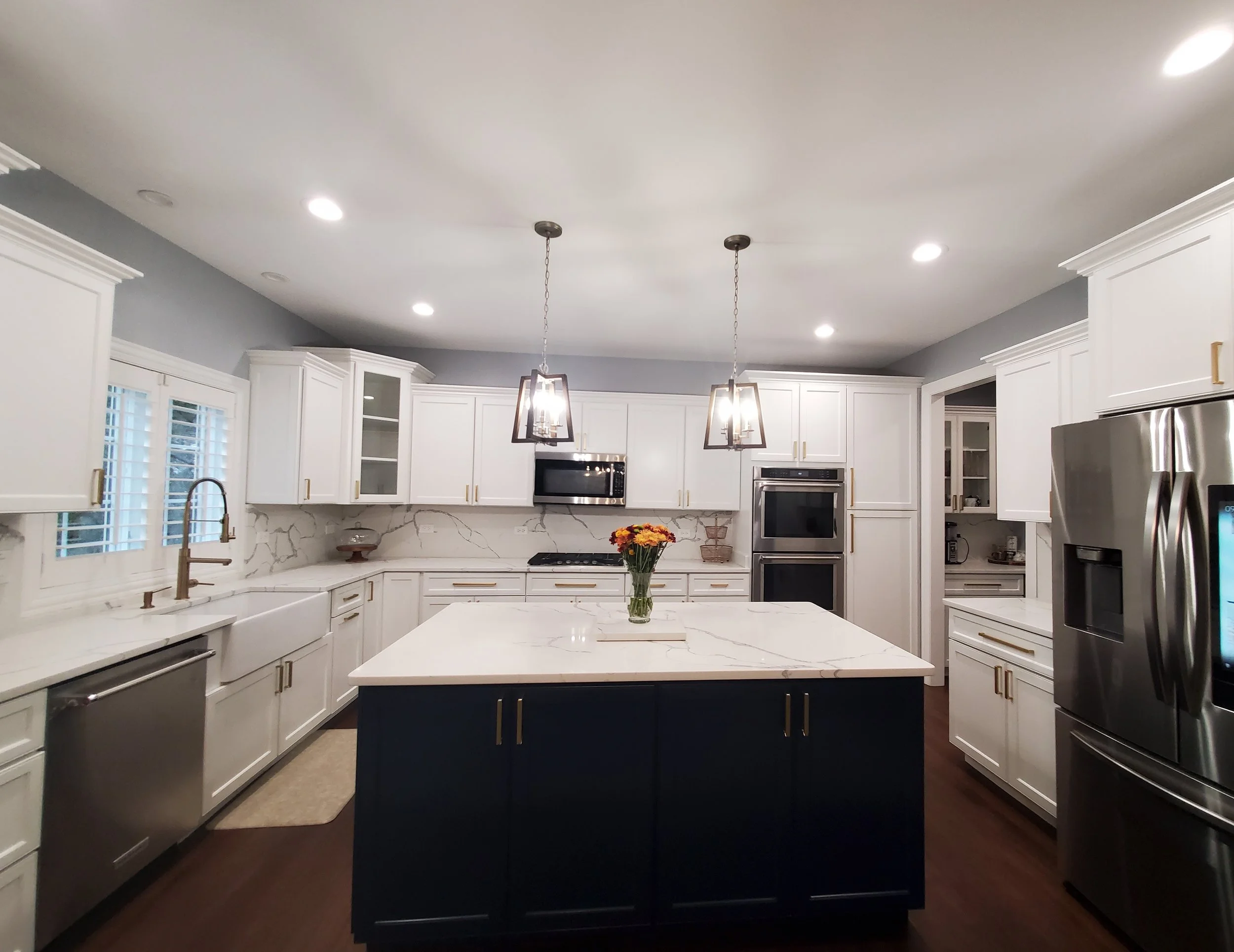 Modern two-tone kitchen cabinet transformation with navy blue island and white perimeter cabinets.