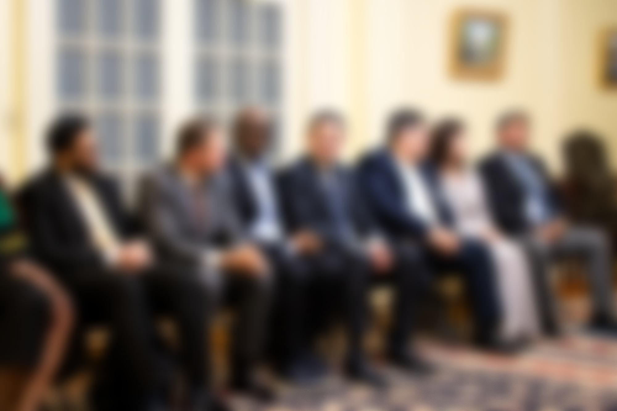 People sitting in a row during a meeting or conference in a formal setting.