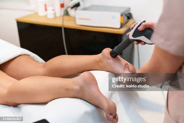 White hand and body cream bottle with black pump, placed on a white marble stand, with a silver container nearby, and eucalyptus leaves above.