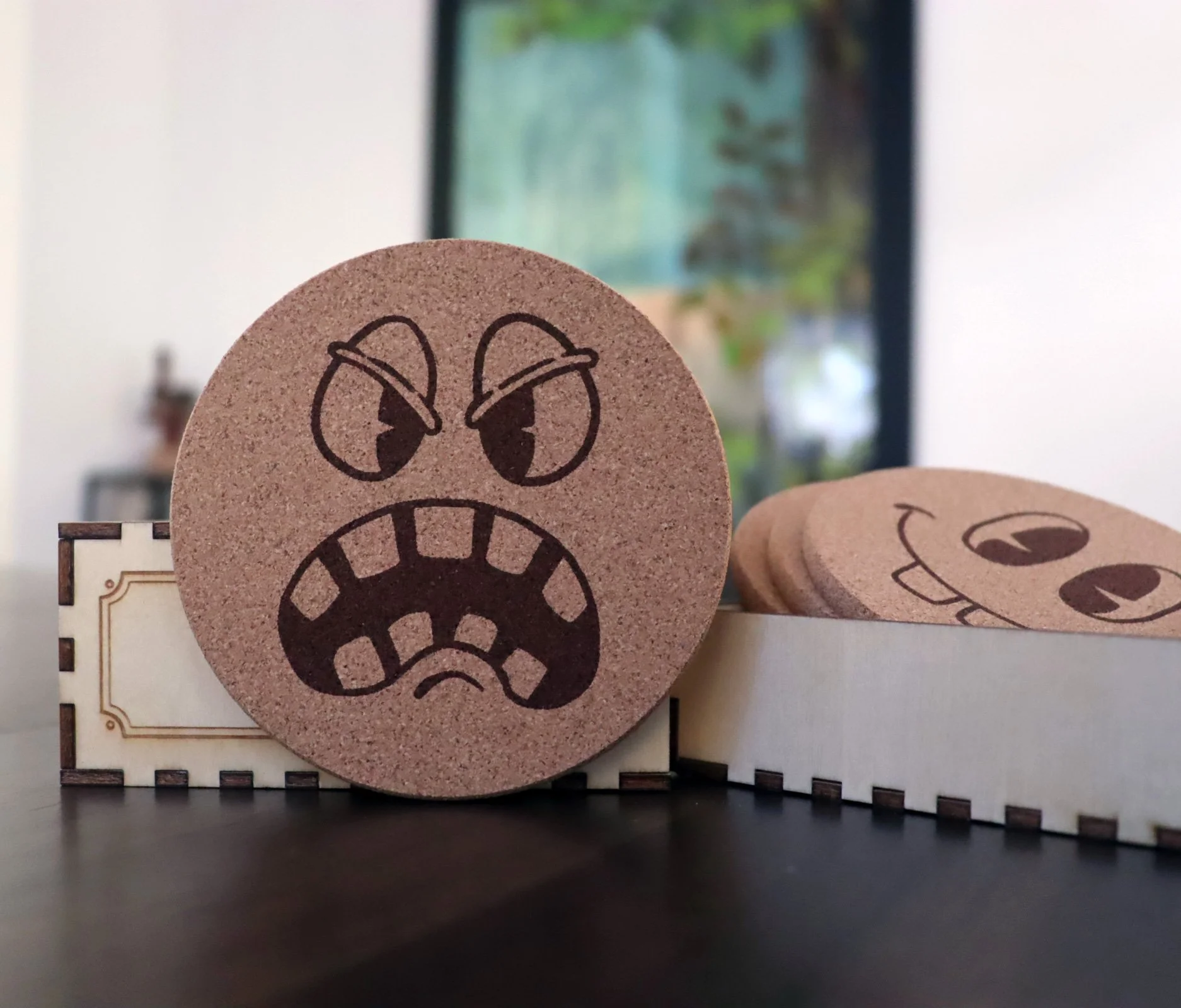 Hoppin_Mad Cork coaster engraved with cheerful pie-eyed cartoon face
