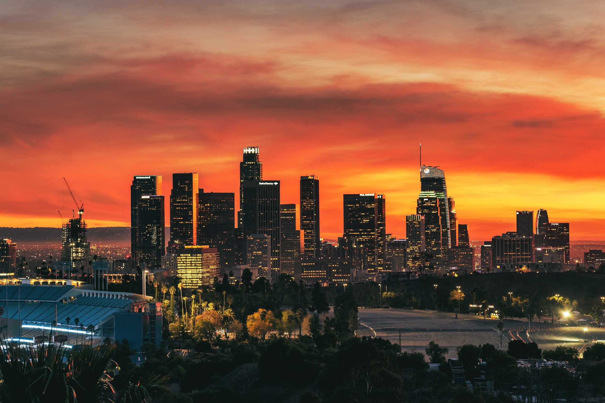 City skyline during sunset with tall skyscrapers and orange sky.