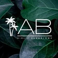 Logo for Airlie Bungalows featuring two palm trees and green leaves in the background.