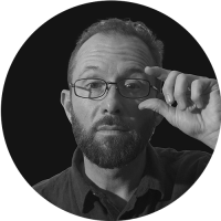 Black and white portrait of Mat McCosker, VFX Supervisor at LVL UP Digital, adjusting his glasses in a studio-style headshot.