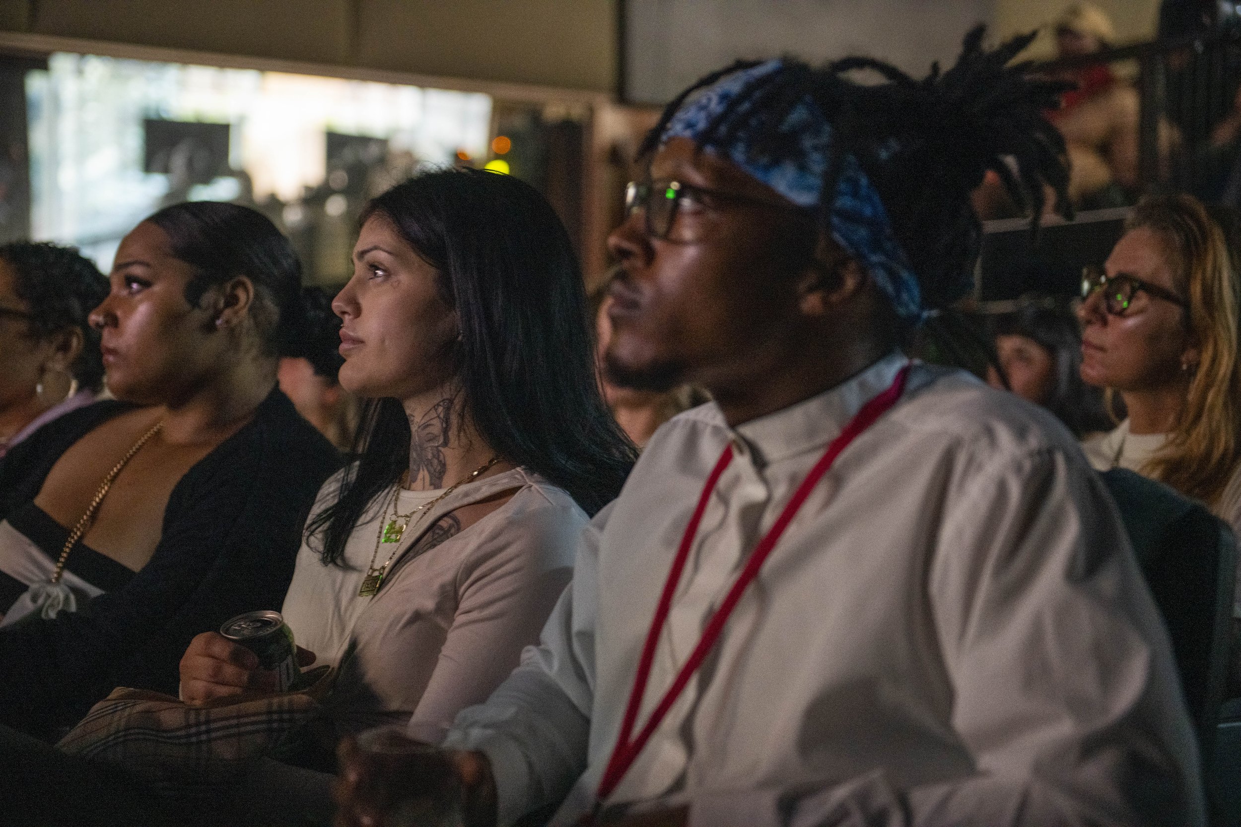 Audience members attentively watching a presentation at an indoor event.
