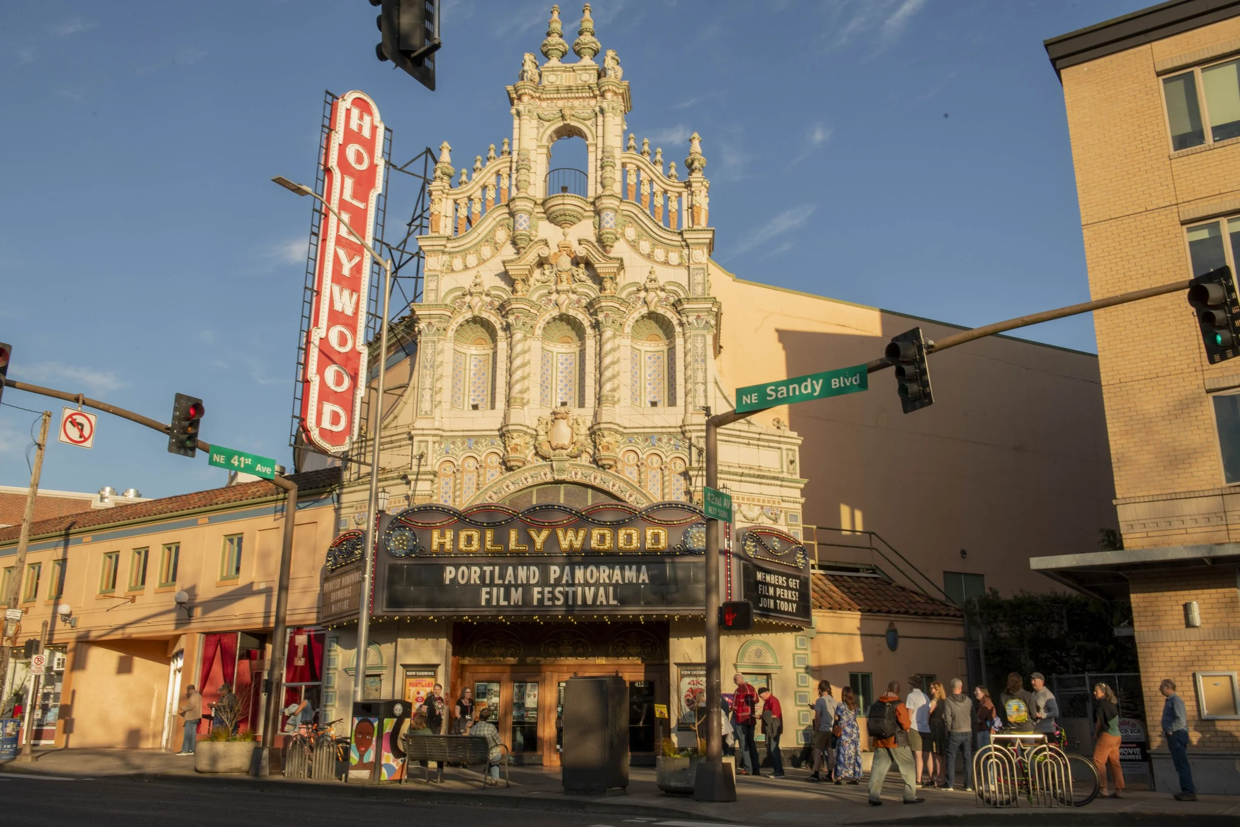 The Hollywood Theatre at Portland Panorama Film Festival on a sunny day with people walking on the sidewalk.