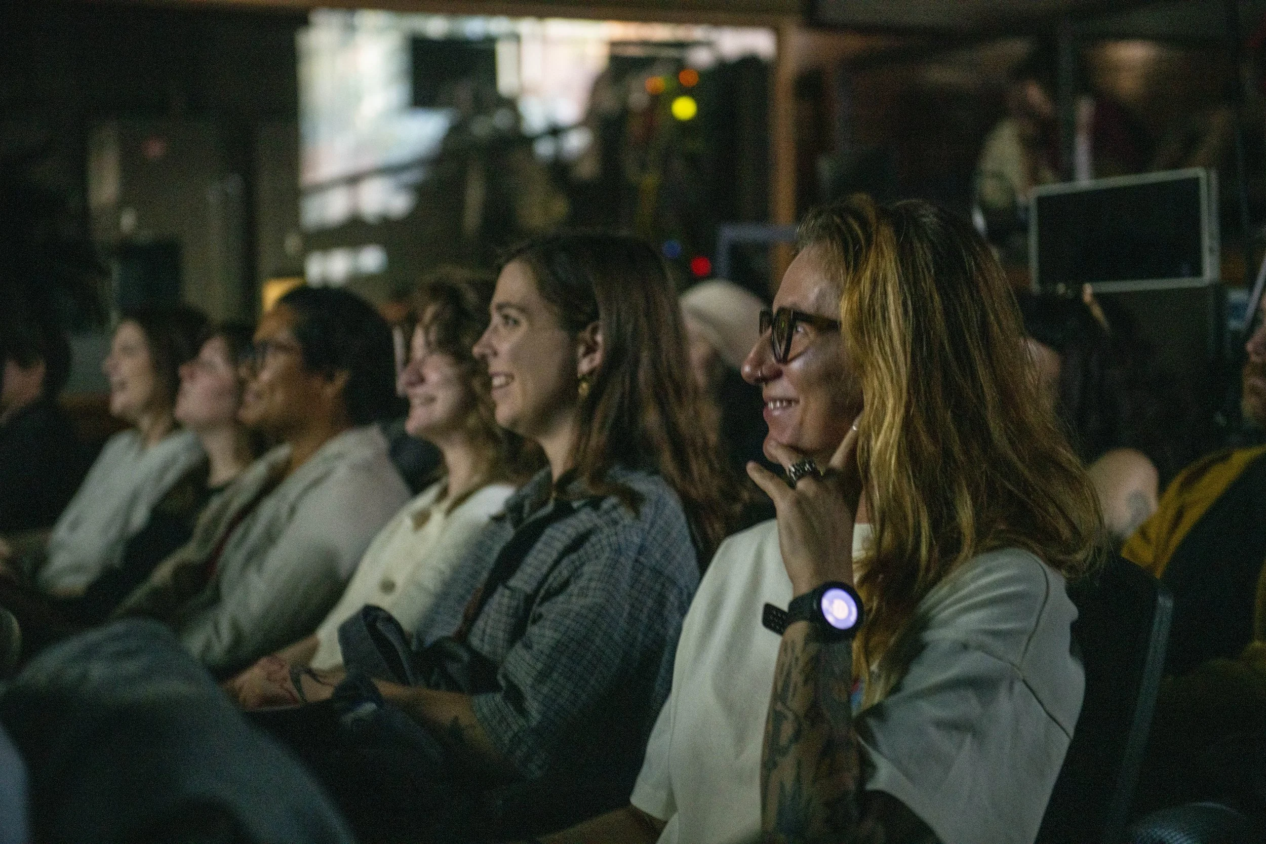 Group of diverse people sitting in audience at an event, smiling and engaged.