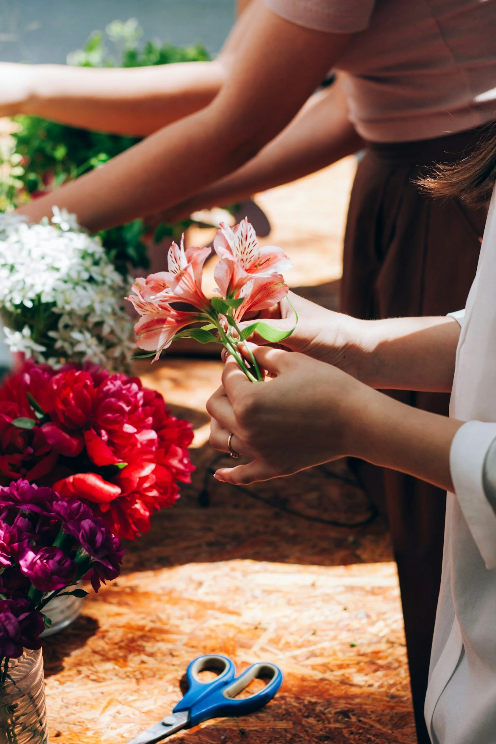People arranging colorful flowers at a florist table.
