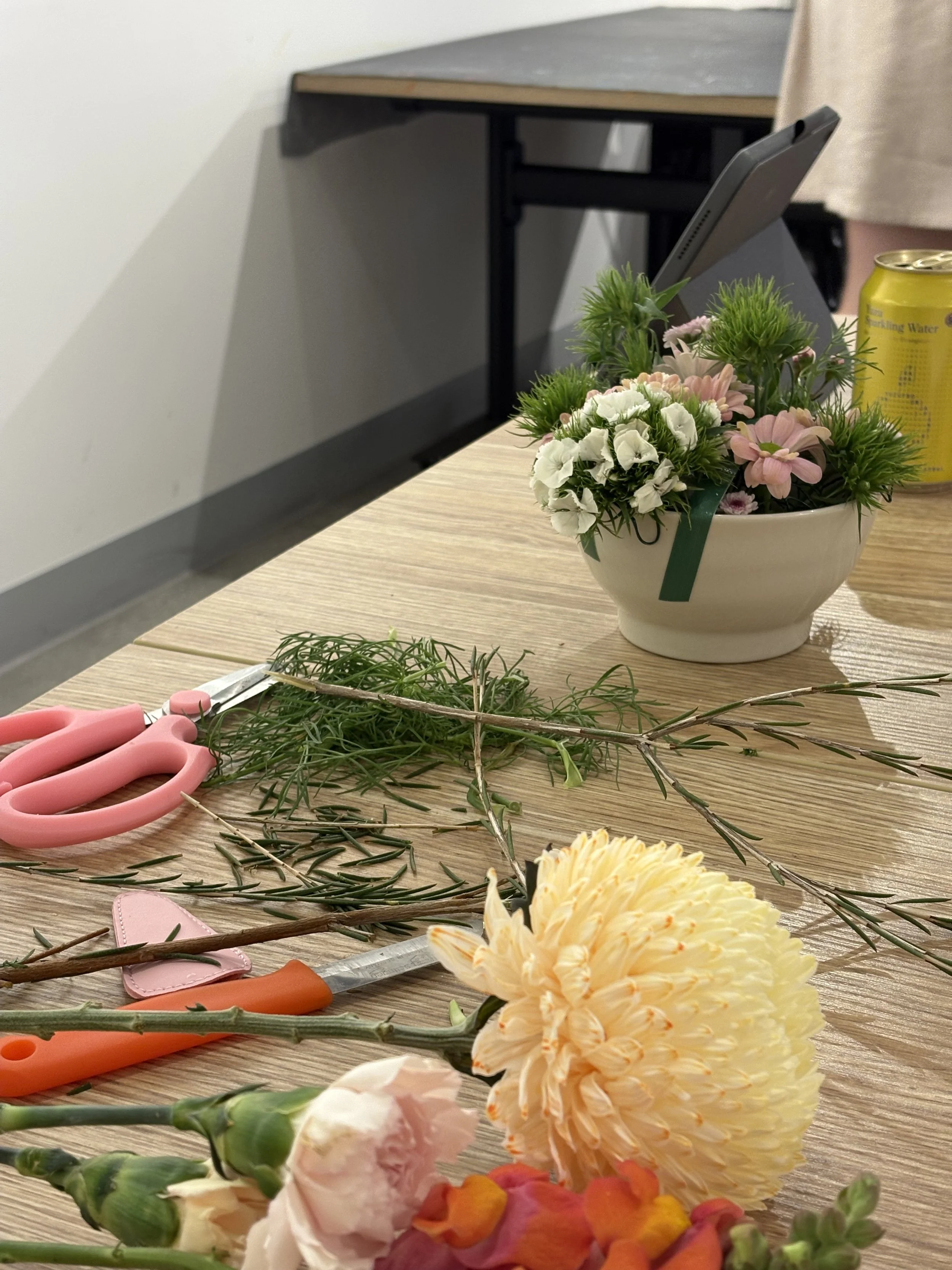 Floral workshop image consisting of beautiful blooms, a messy table and scissors.