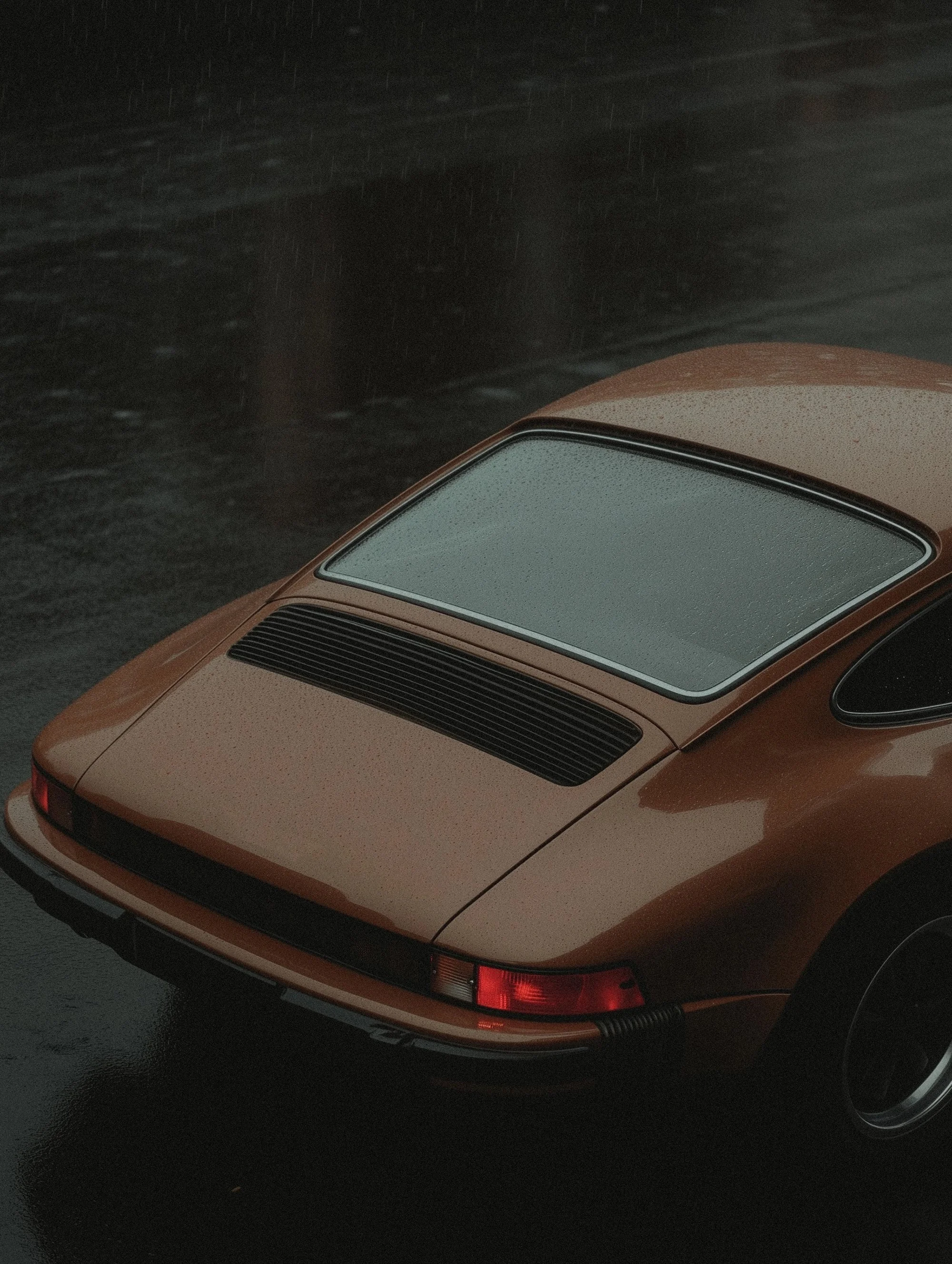 Vintage orange car parked on wet asphalt