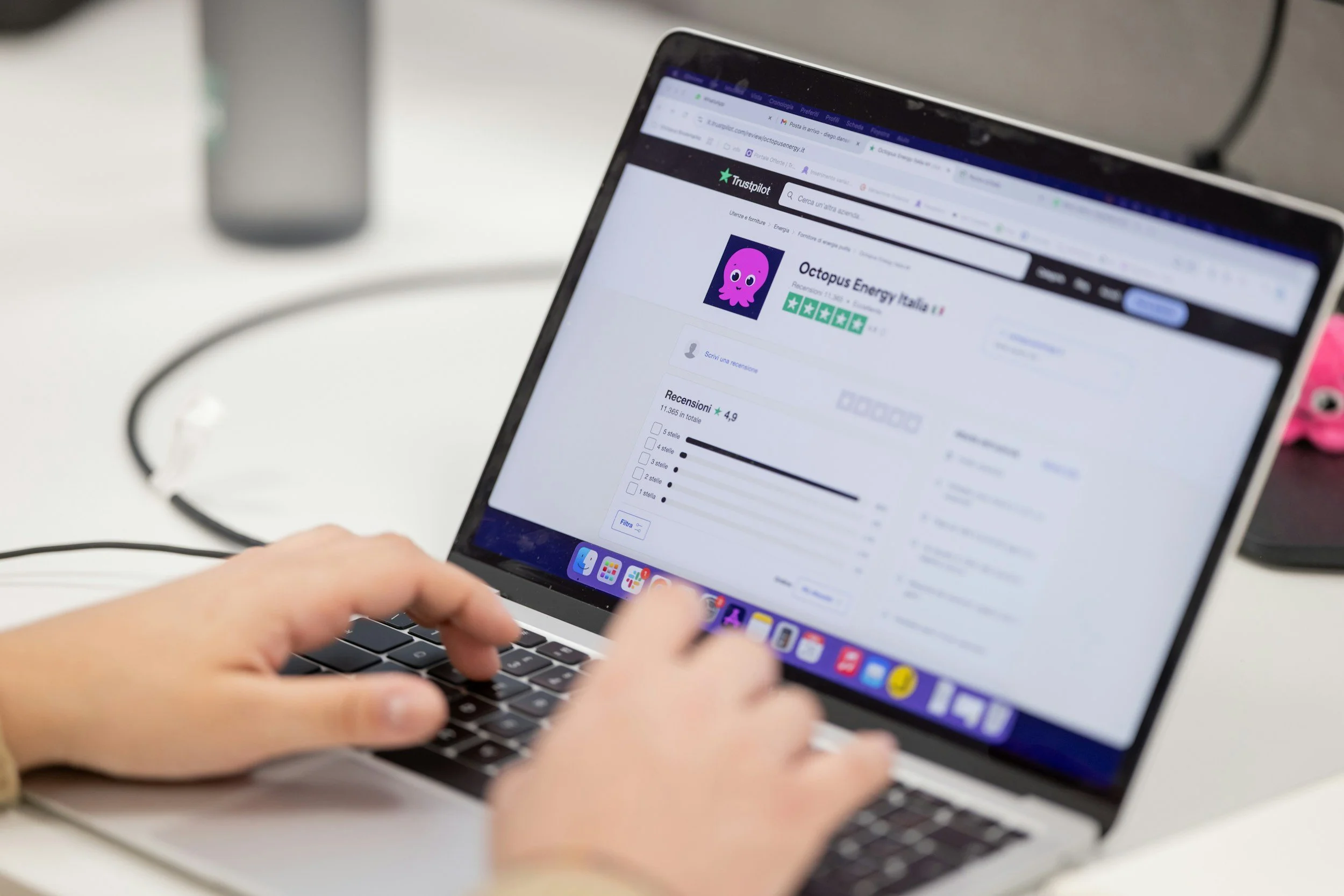 Person using a laptop to view a webpage with a review for Octopus Energy Italia on Trustpilot.