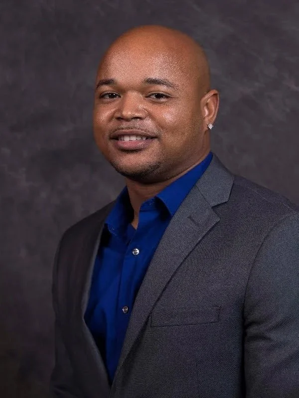 Headshot of a man in a gray blazer and blue shirt against a dark background. Tax professionals Murfreesboro, TN