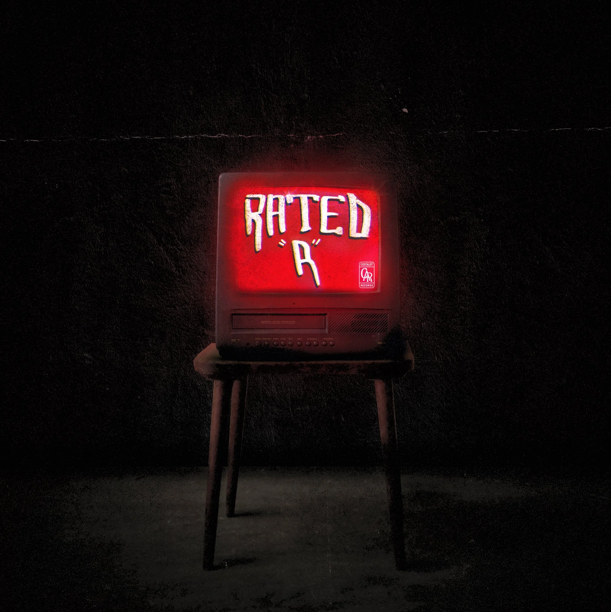 Vintage television on a wooden stool displaying a red neon sign that reads 'RATED R' with a pointing hand icon, against a dark background.