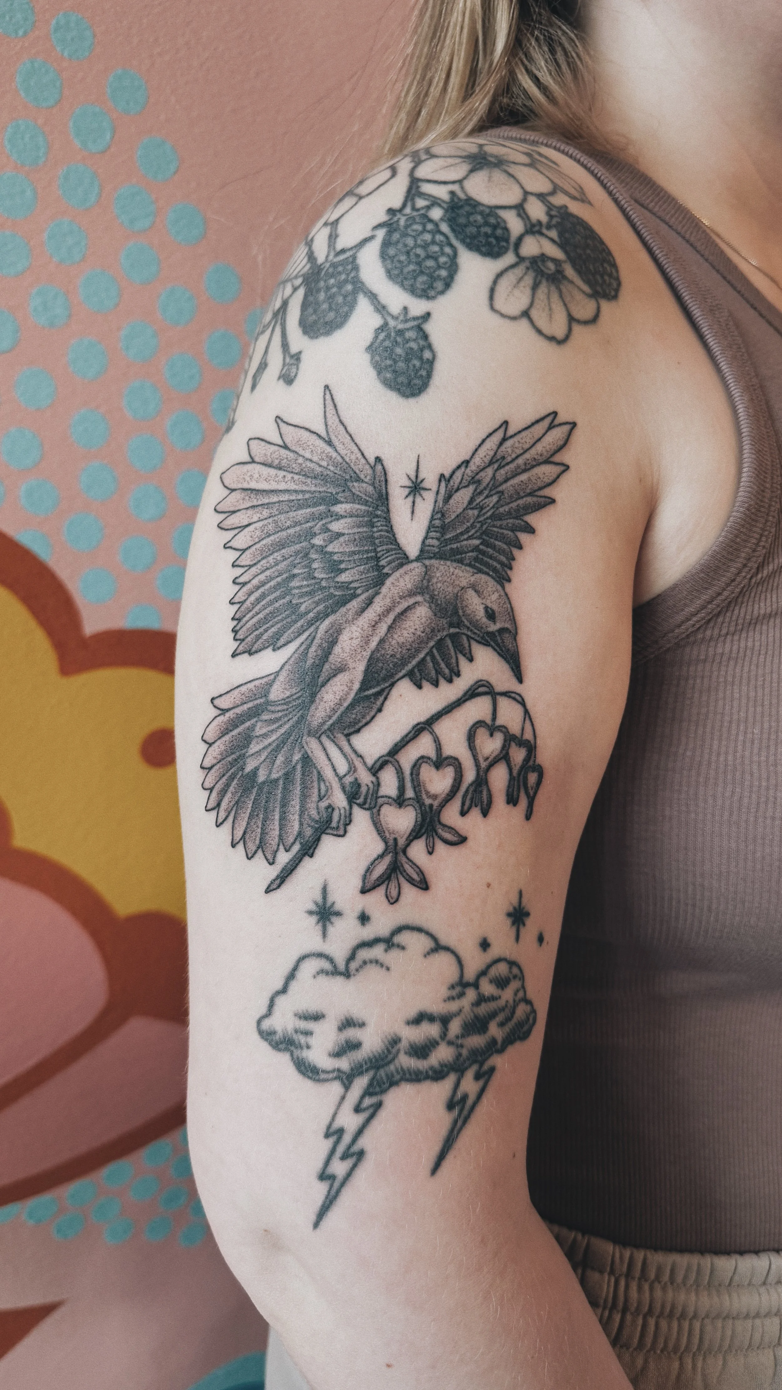 Black and grey dotwork tattoo of a raven holding a branch of bleeding hearts and a start tucked between its wings