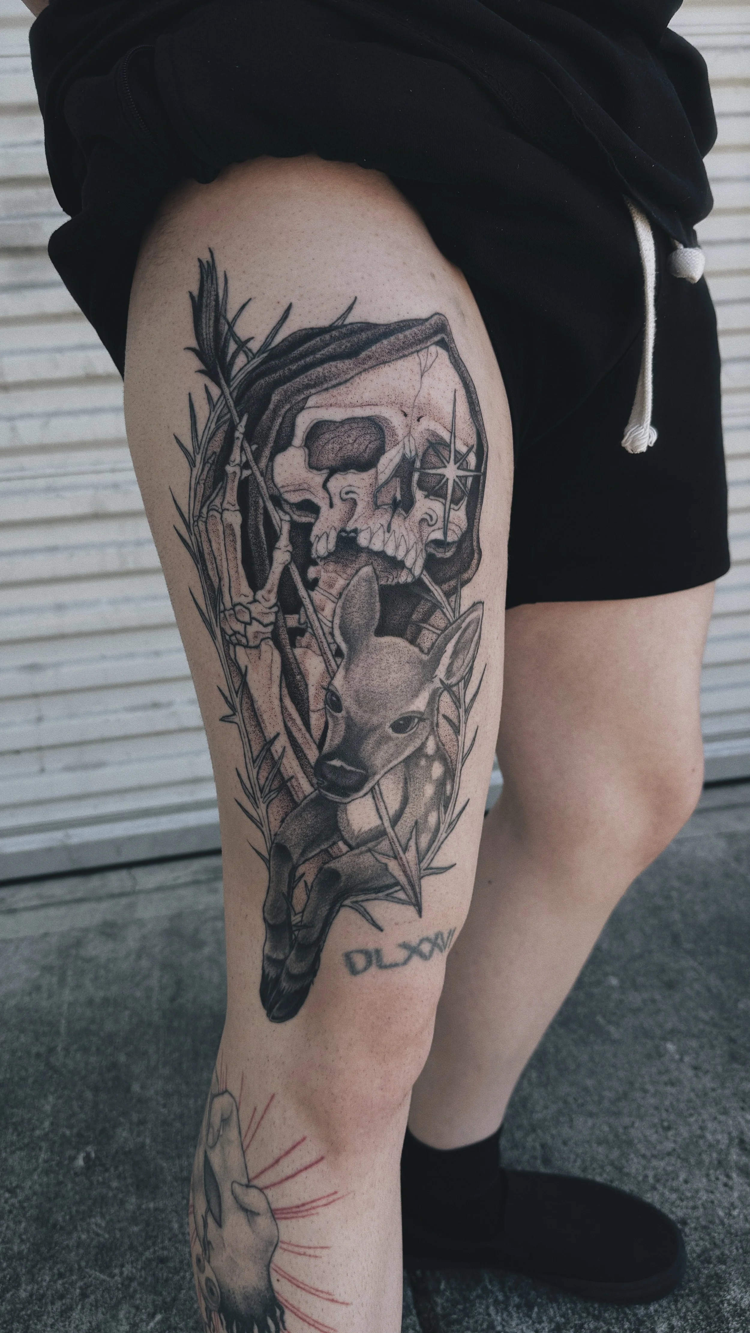 large thigh black and grey dotwork tattoo of a reaper holding onto a fawn deer and arrow, theres a diamond in the reapers eye and he looks sadenned