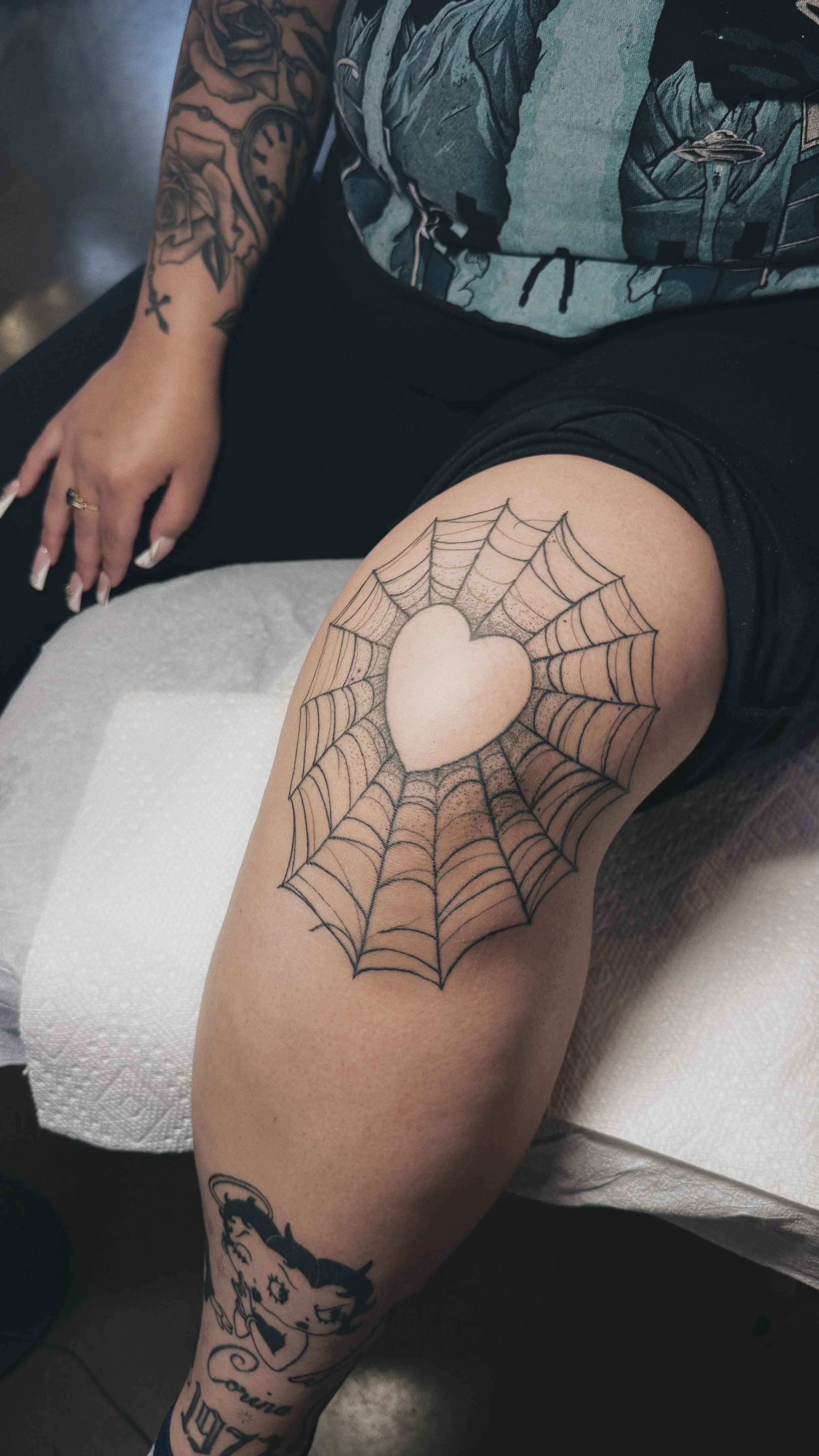 knee tattoo of a spiderweb with a heart in the center, dotwork texture