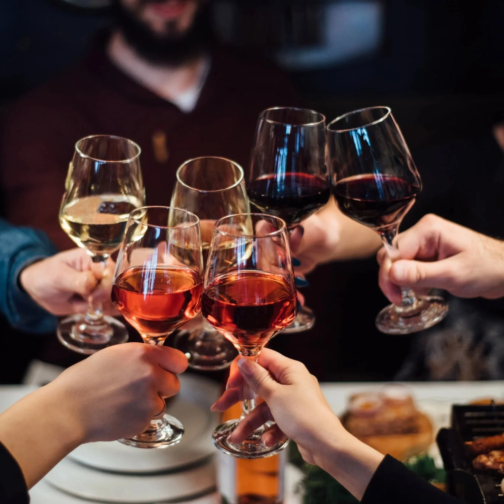 Group of people toasting with glasses of red and white wine.