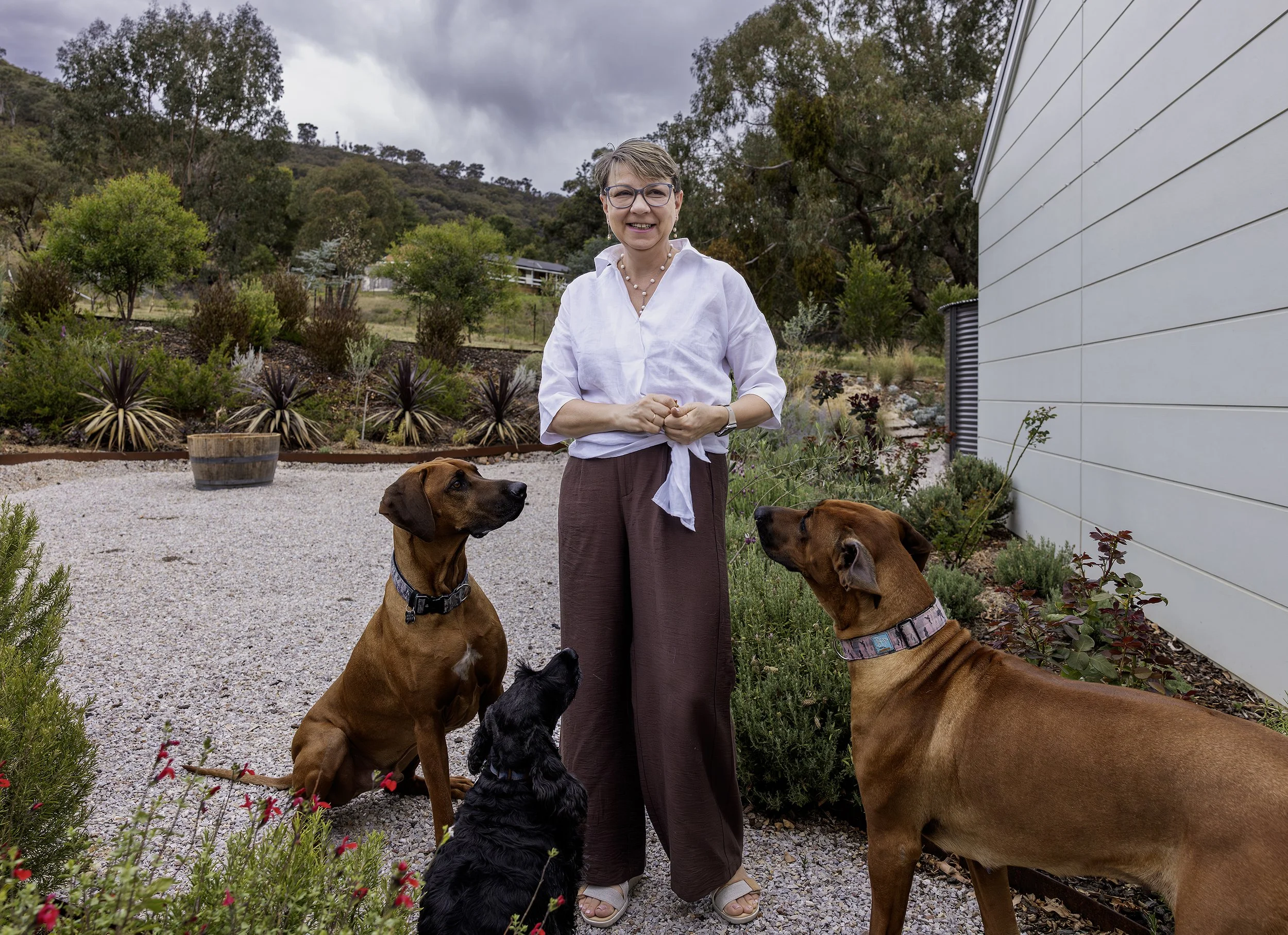 Pet photographer enjoying a playful moment with dogs during a relaxed photography session in a garden
